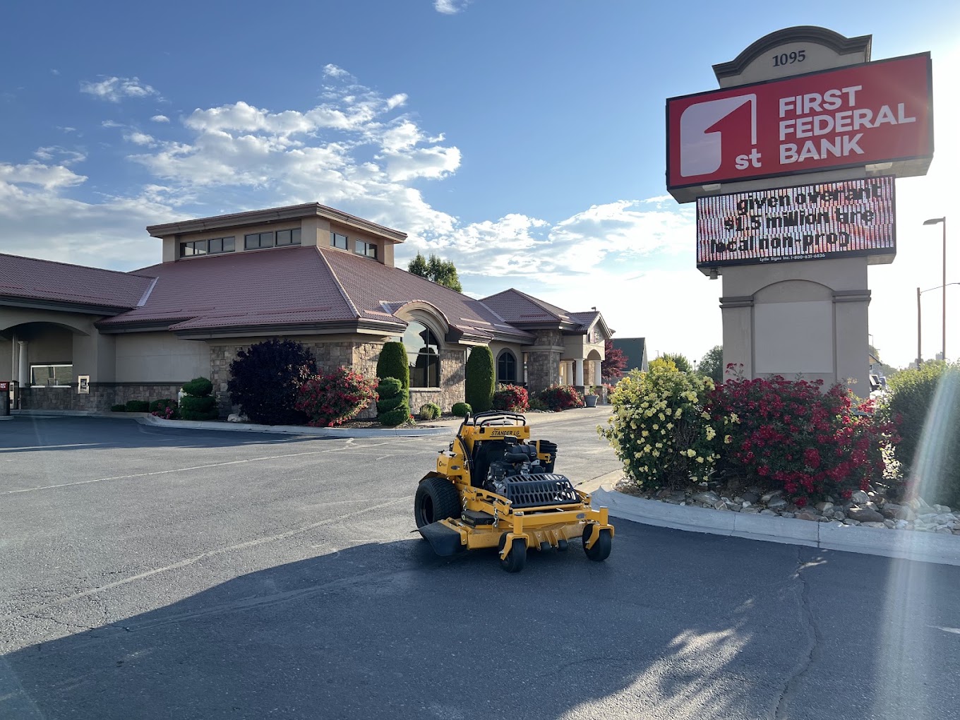 Commercial mower parked at a bank property with maintained flower beds